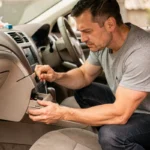 Homme tentant de débloquer la boîte à gants coincée d'une Ford Mondeo depuis le siège passager