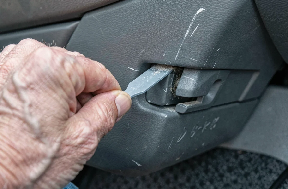 Gros plan sur l'outil de déblocage inséré dans le mécanisme du verrou de boîte à gants Ford Mondeo